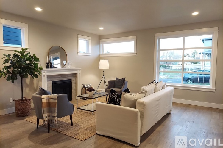 A living room with a fireplace, two chairs, a couch, and a potted plant.
