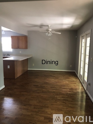A dining room with wooden floors and a ceiling fan.