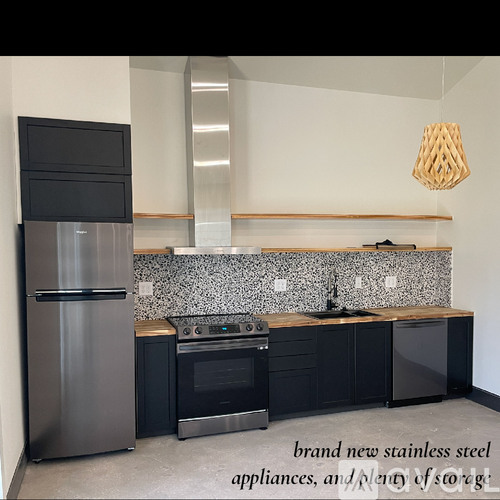 A modern kitchen with stainless steel appliances and black cabinets.