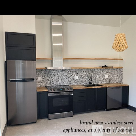 A modern kitchen with stainless steel appliances and black cabinets.