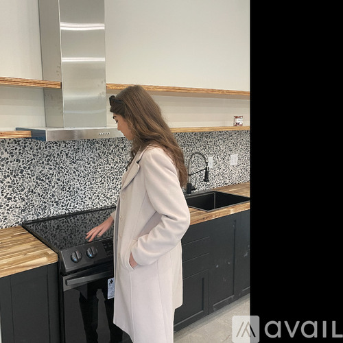 A woman in a white coat is standing in a kitchen.
