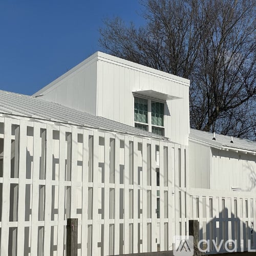 A white building with a window and a lattice fence.