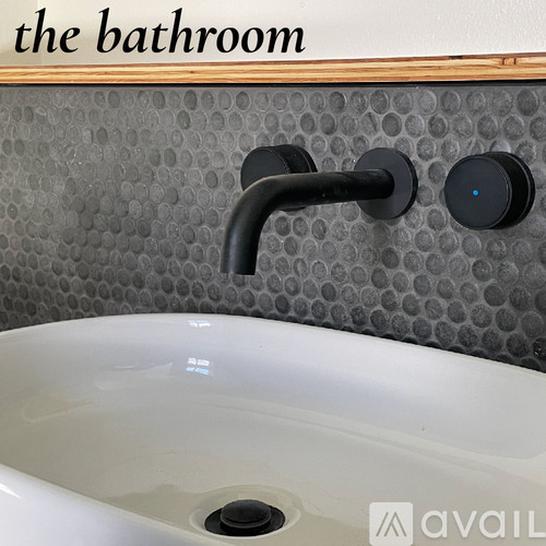 A bathroom sink with a black faucet and a wall-mounted control panel.