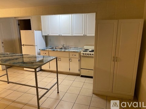 A kitchen with white cabinets and a glass table.