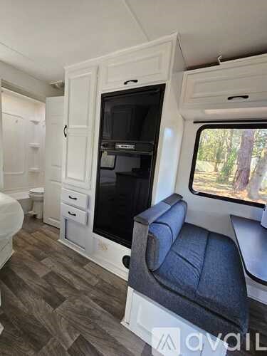 A small, white RV with a grey couch and a black countertop.