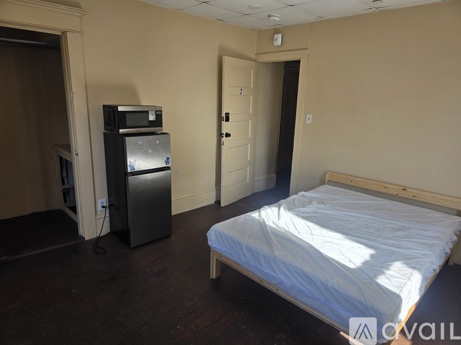 A bedroom with a bed, a fridge, and a cabinet.