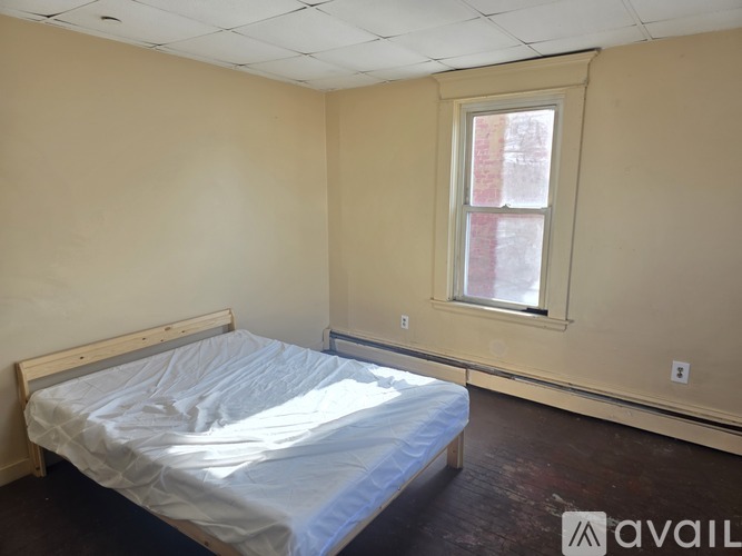 A bedroom with a bed, a window, and a wooden headboard.