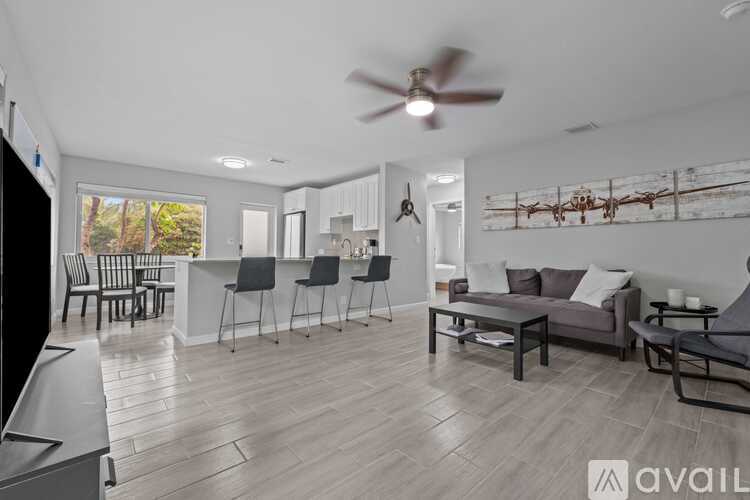A living room with a grey couch, a black chair, and a ceiling fan.