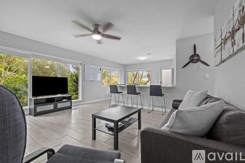 A living room with a grey couch, a black coffee table, and a television on a wooden stand.