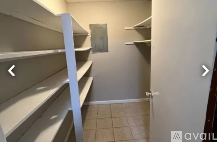 Empty pantry with white shelves and a door on the right.