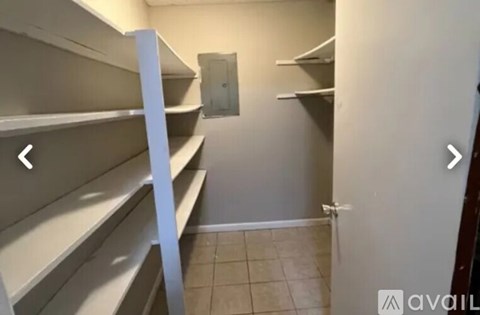 Empty pantry with white shelves and a door on the right.
