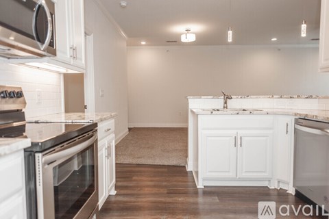 A kitchen with white cabinets and a wooden floor.