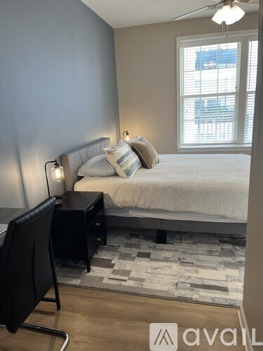 A bedroom with a bed, desk, and window.