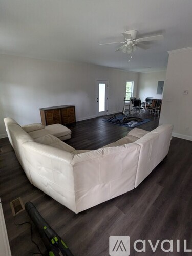 A white sofa in a room with a ceiling fan.