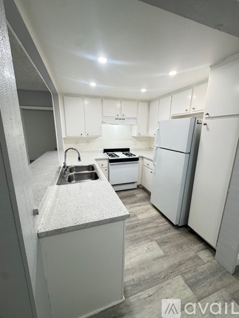 A kitchen with white cabinets and a grey island.