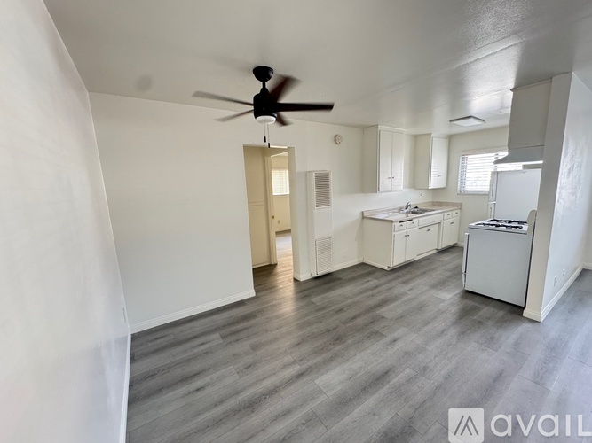 A spacious room with a ceiling fan and a kitchenette.