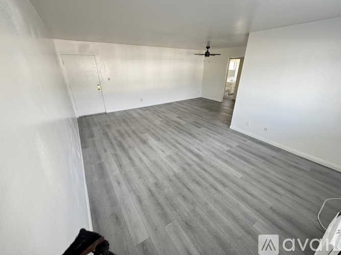 A room with a ceiling fan and light, and a door on the left.