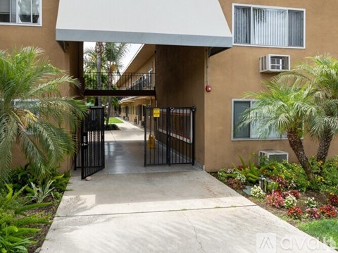 A gated entrance to a building with a white awning and a concrete pathway.