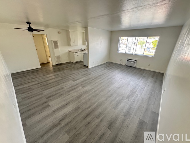 A spacious room with a ceiling fan and a window with blinds.