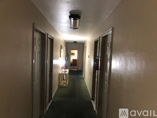 A long hallway with doors on both sides and a light on the ceiling.