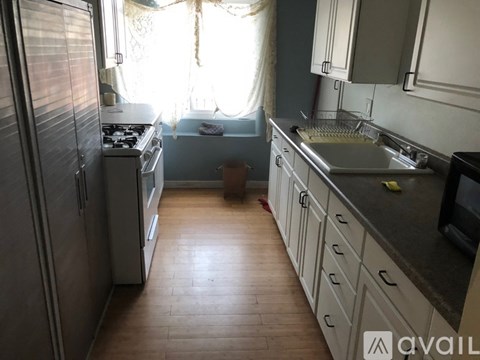 A kitchen with wooden floors and a refrigerator on the left.