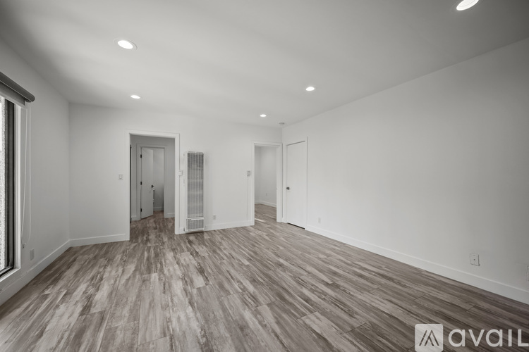 A spacious room with wooden flooring and white walls.