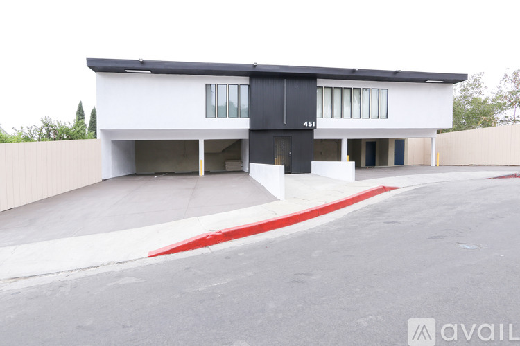 A modern house with a black and white exterior and a red stripe on the driveway.