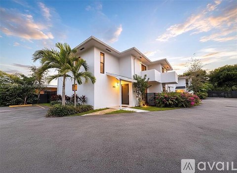 A modern white house with a palm tree in front.