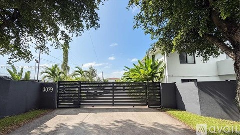A house numbered 3079 is surrounded by a black fence and has a gate.