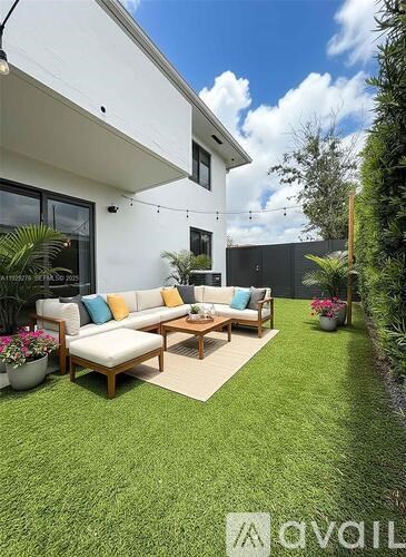 A modern outdoor seating area with a white couch and wooden coffee table.