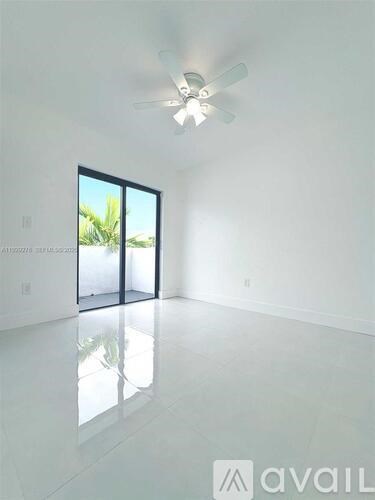 A spacious room with a ceiling fan and a large window.