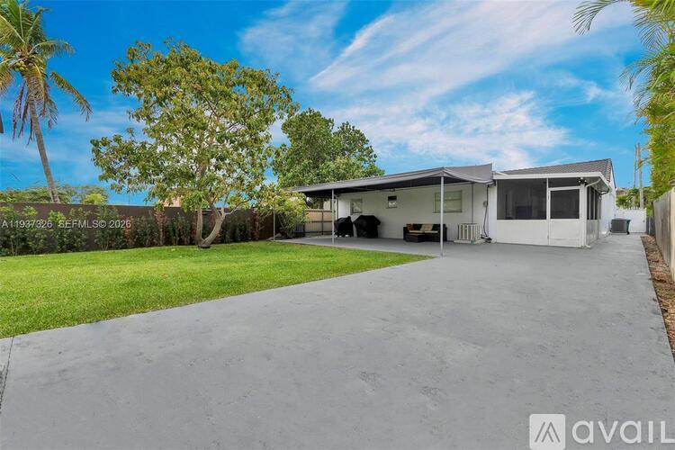 A modern house with a large driveway and palm trees in the background.