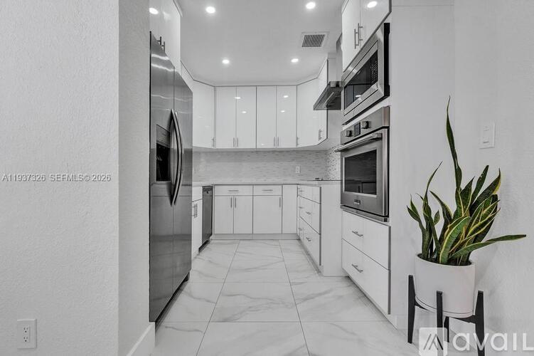 A modern kitchen with white cabinets and appliances.