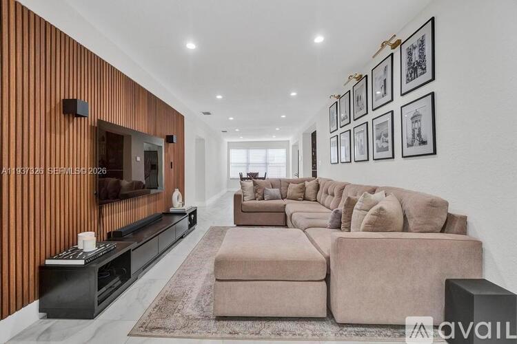 A modern living room with a long couch and a flat screen TV mounted on the wall.