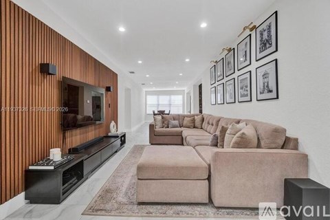 A modern living room with a long couch and a flat screen TV mounted on the wall.