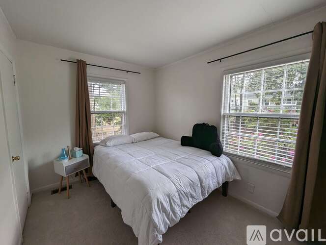 A bedroom with a large bed and a window with blinds.