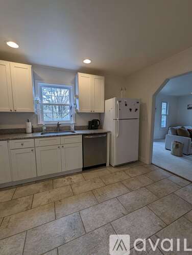 A kitchen with white cabinets and a white refrigerator.