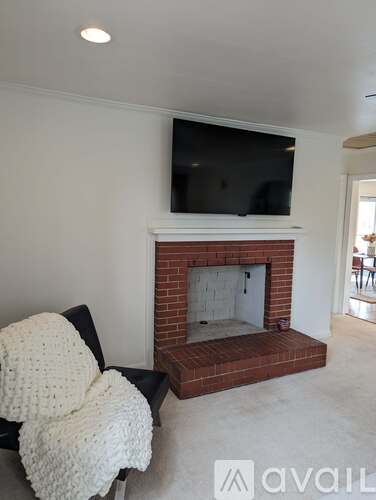 A living room with a fireplace and a television mounted above it.
