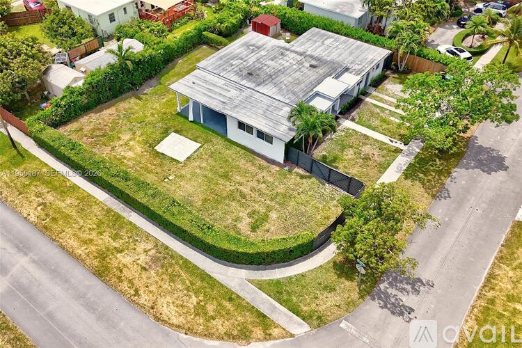 A house with a grey roof is surrounded by a green lawn.