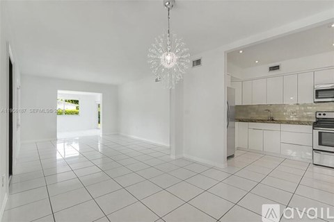 A spacious kitchen with white tiled floors and a chandelier hanging from the ceiling.