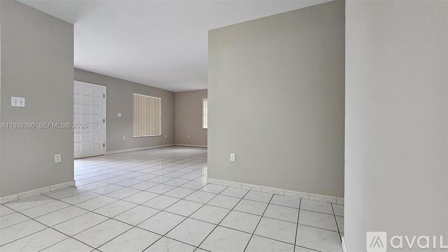 A spacious room with white tiled flooring and beige walls.