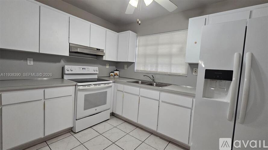 A white kitchen with a refrigerator, oven, and sink.
