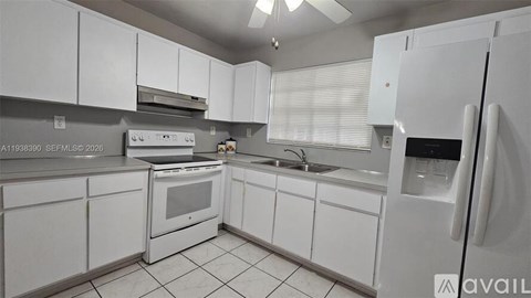 A white kitchen with a refrigerator, oven, and sink.