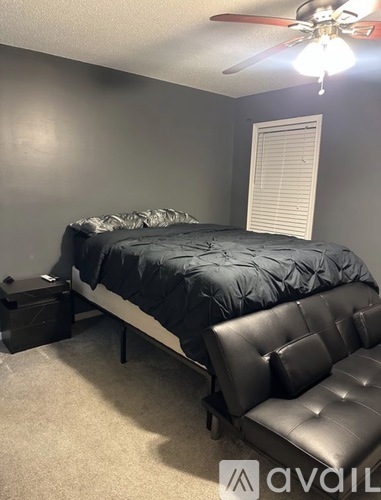 A bedroom with a bed, a bench, and a ceiling fan.