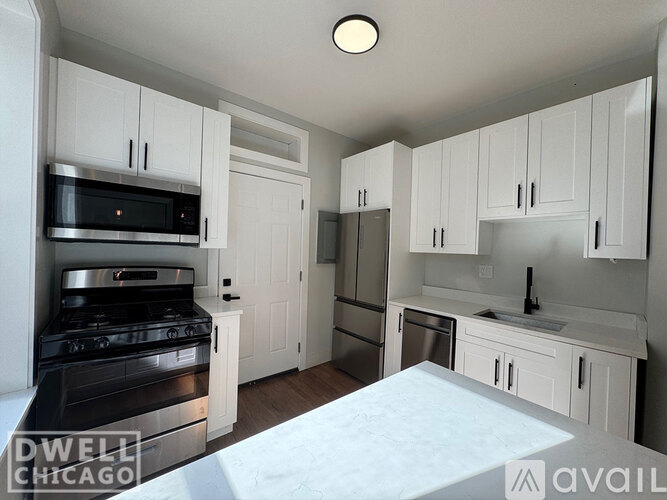 A kitchen with white cabinets and a stove top oven.