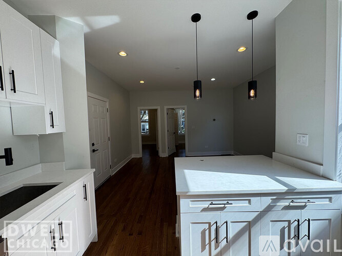 A kitchen with white cabinets and a wooden floor.
