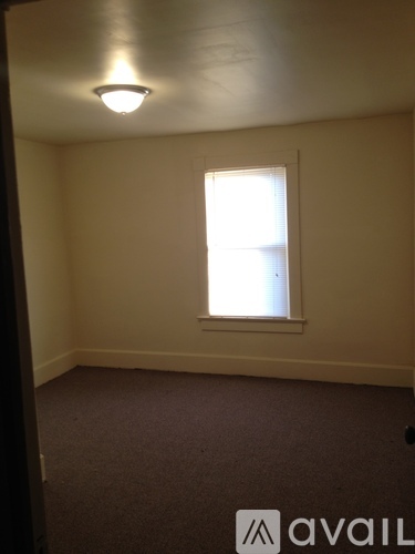 A carpeted room with a window and a light on the ceiling.