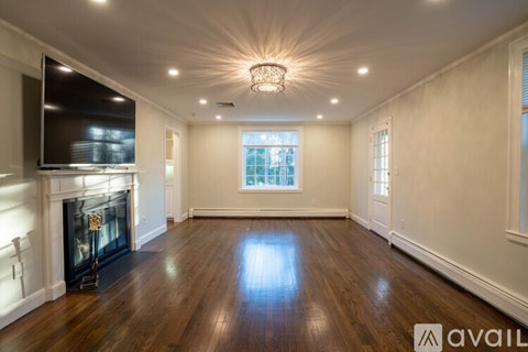 A spacious living room with wood flooring and a fireplace.