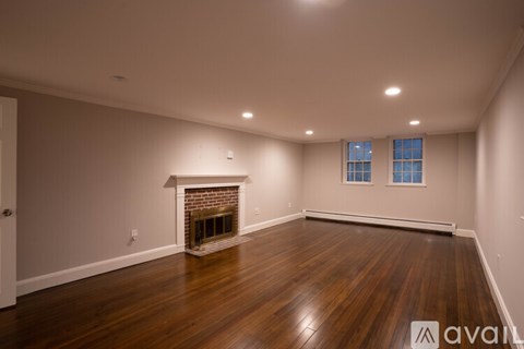 A spacious room with a fireplace and wooden flooring.