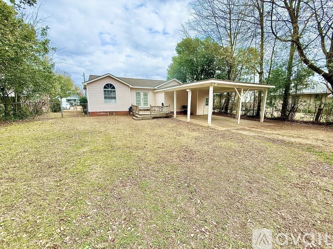 A house with a covered porch is surrounded by a grassy area.